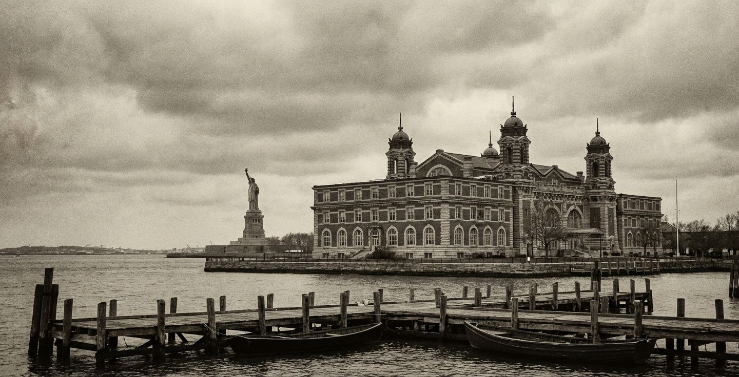 A black and white photograph of the Ellis Island immigration building with the Statue of Liberty in the background